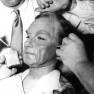 Make-up artists applying adhesive to Dr. Smith mask